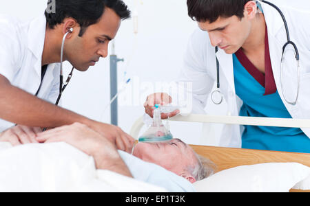 Junger Arzt putting Sauerstoffmaske auf eine ältere Patienten Stockfoto