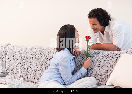 Frau bekam eine Rose von ihrem Freund im Wohnzimmer Stockfoto