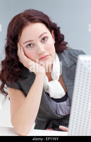 Junge Geschäftsfrau vor einem Computer Langeweile Stockfoto