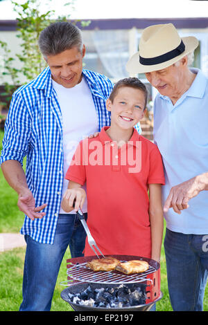 Erholsamen senior Mann, junger Mann und junge kochen Fleisch am grill im freien Stockfoto