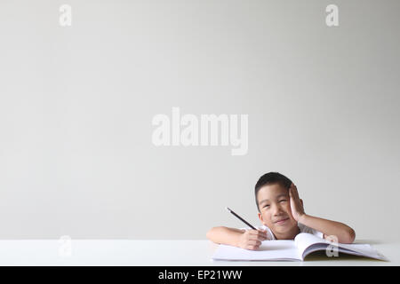 Junge sitzt auf einer Tabelle studieren Stockfoto