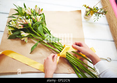 Weibliche Floristen binden frisches Bouquet mit gelben Band Stockfoto