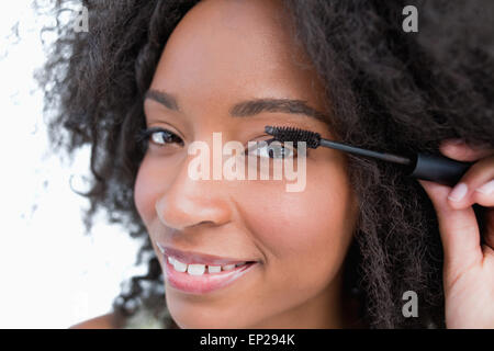 Junge lächelnde Frau Anwendung Mascara auf ihre Wimpern Stockfoto