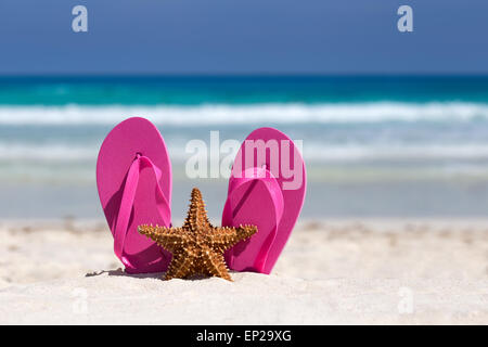 Rosa Flip Flops und Seesterne am weißen Sandstrand. Sommer Urlaub Konzept Stockfoto