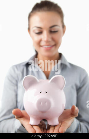 Nahaufnahme von Sparschwein durch weibliche Bank Assistent statt Stockfoto