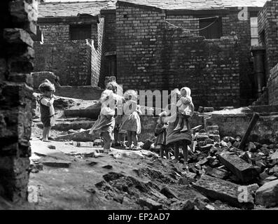 Kinder spielen in einem abgerissenen Wohngebiet angrenzend an ihren eigenen Häusern zwischen Sim und Seite Street, Liverpool, Merseyside. Weiß für die Zeitung "Daily Herald" am 12. Juli 1954 getroffenen. Stockfoto