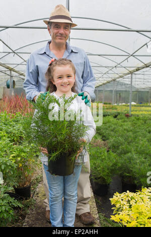 Kleines Mädchen hält Topfpflanze mit Großvater Stockfoto