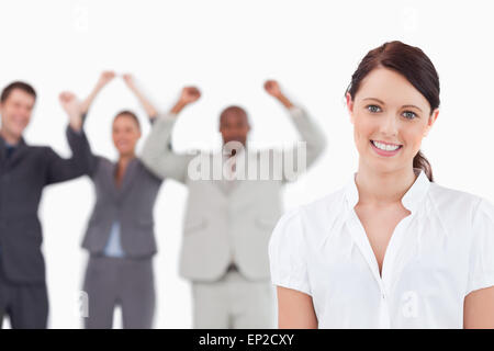 Verkäuferin mit Feiern Kollegen hinter ihr Lächeln Stockfoto