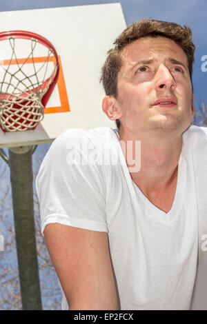 Junger Mann, ruhen Sie sich nach anstrengenden Basketball-Spiel Stockfoto