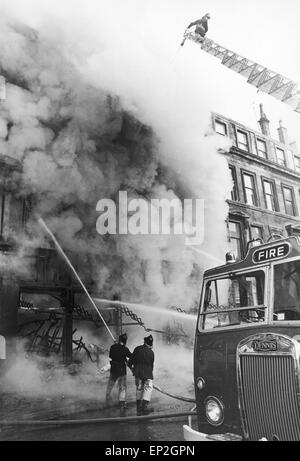 Feuer bei Maryhill Road Glasgow. Feuer bricht in einen unbesetzten Möbelgeschäft Verbreitung entlang der Ladenzeile und fangen einige Familien in ihren Häusern oben. Fünfzig Familien wurden obdachlos, und eine Frau und ein Feuer Offizier ums Leben. Samstag, 18. November 1972. Im Bild zwei Feuerwehrleute versuchen, den Brand zu löschen. Stockfoto