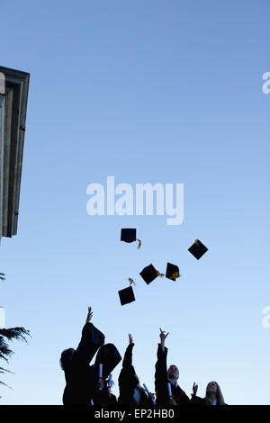 Fünf Grad Studenten werfen ihre Hüte in den Himmel Stockfoto