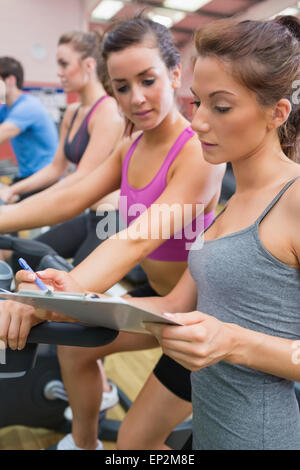 Gym Instructor helfende Frau am Ergometer Stockfoto