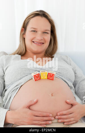 Entzückende blonde Frau mit Mama Buchstaben auf den Bauch Stockfoto