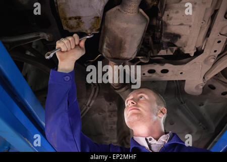 Konzentriert, Mechaniker mit Blick auf die unterhalb eines Autos Stockfoto