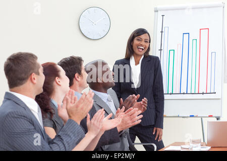 Business-Leute applaudieren ihrer Kollegin in einer Besprechung Stockfoto
