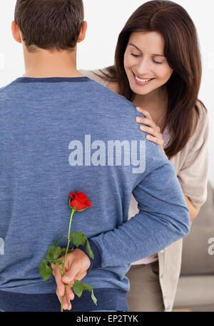 Impatiente Frau betrachten einer Blume versteckt von ihrem Freund Stockfoto