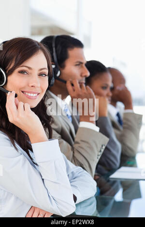 Lächelnde Callcenter-Agent schaut in die Kamera während der harten Arbeit Stockfoto