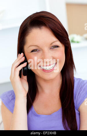 Junge Frau am Telefon zu Hause lachen Stockfoto