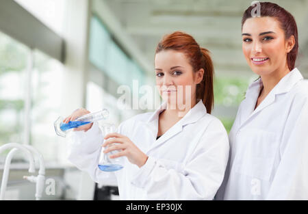 Wissenschaftler, die blaue Flüssigkeit in einen Erlenmeyerkolben gießen Stockfoto