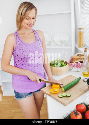 Konzentrierte sich Frau schneiden Paprika und Gurken zu Hause Stockfoto