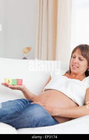 Gut aussehend schwangere Frau spielen mit Holzklötzen und haben das Wort junge geschrieben auf ihrer Hand Stockfoto