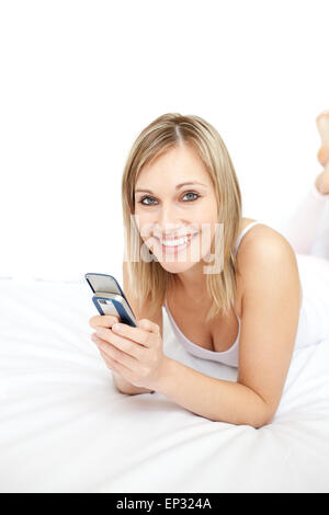 Jolly Frau eine SMS auf ihrem Bett liegend Stockfoto
