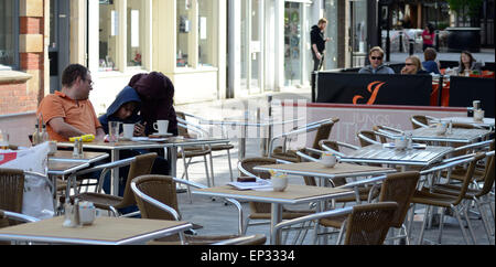 Ein Vater und seine beiden Söhne sind hier in etwas auf einem Smartphone als das sitzen und ihre Getränke außerhalb in einem Café zu beenden. Stockfoto