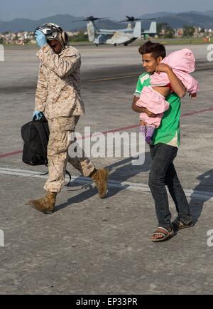 Kathmandu, Nepal. 13. Mai 2015. Ein US-Marine mit gemeinsamen Task Force 505 hilft ein Mann und sein Kind, eine medizinische Triage am Tribhuvan International Airport 12. Mai 2015 in Kathmandu, Nepal. Ein 7,3 Größenordnung Nachbeben Erdbeben das Königreich nach dem Erdbeben der Stärke 7,8 am 25. April. Stockfoto