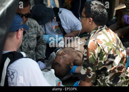 Kathmandu, Nepal. 13. Mai 2015. Ein US-Flieger, nepalesischen Soldaten und Such- und Rescuemen von Fairfax County Virginia, helfen Sie einem nepalesischen Mann im Triage-Setup an der Tribhuvan International Airport 12. Mai 2015 in Kathmandu, Nepal. Ein 7,3 Größenordnung Nachbeben Erdbeben das Königreich nach dem Erdbeben der Stärke 7,8 am 25. April. Stockfoto