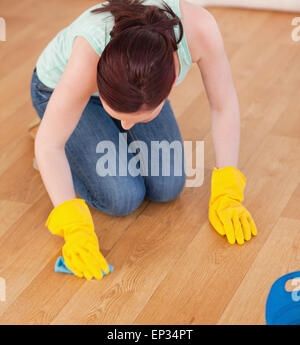 Attraktive rothaarige Frau, die Reinigung des Bodens kniend Stockfoto