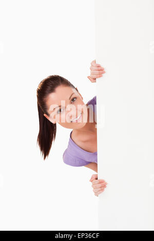 Porträt einer schönen Frau posiert hinter einer Plakatwand Stockfoto
