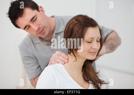 Lächelnde Frau sitzend und von einem Mann massiert Stockfoto
