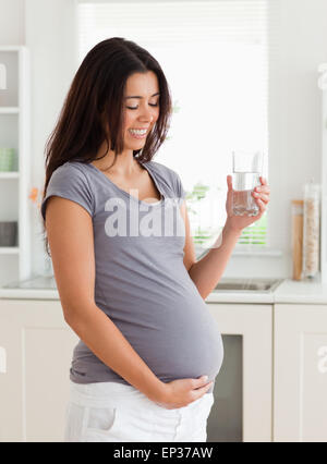 Charmante schwangere Frau mit einem Glas Wasser stehend Stockfoto