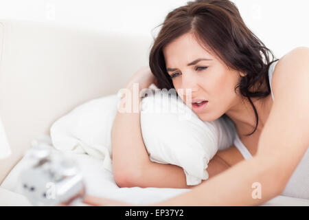 Brünette Frau beim Blick auf ihren Wecker aufwachen Stockfoto