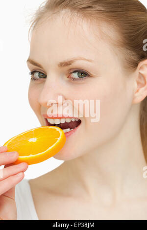 Nahaufnahme einer Frau, die Platzierung einer Orangenscheibe in den Mund Stockfoto