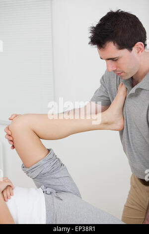 Frau, setzen ihr Bein auf der Brust des Arztes während der Dehnung Stockfoto