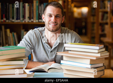 Lächelnde Student umgeben von Büchern Stockfoto
