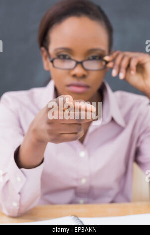 Strenge Lehrerin zeigt der Finger beim Berühren ihrer Brille Stockfoto