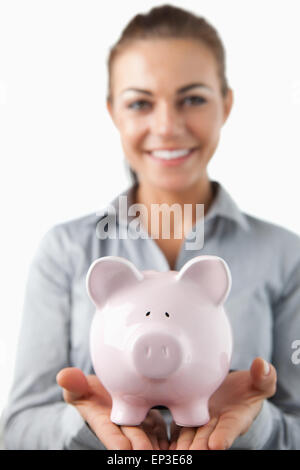 Nahaufnahme von Sparschwein durch weibliche Bank Assista lächelnd statt Stockfoto