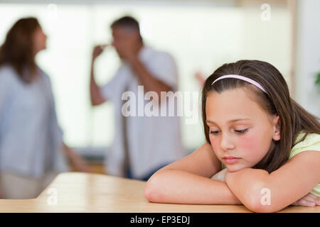 Trauriges Mädchen mit ihren kämpfen Eltern hinter ihr Stockfoto
