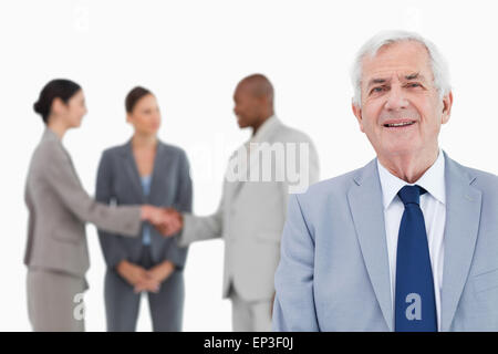 Reife Verkäufer mit Handelspartnern hinter ihm Stockfoto