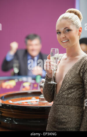 Frau mit Champagner stand neben Roulette-Rad Stockfoto