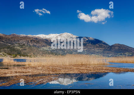 Stymfalia See im Corinthia Präfektur, Griechenland mit den schneebedeckten Bergen als Hintergrund reflektiert in den Gewässern des Sees Stockfoto