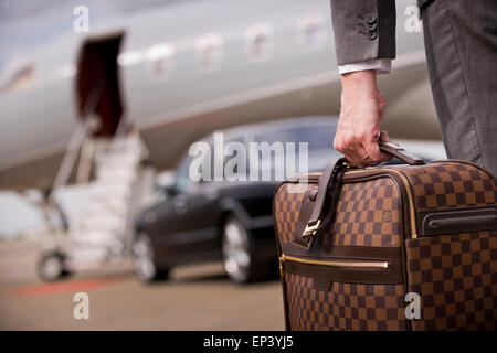 Koffer durchgeführt um ein privates Flugzeug und Luxus Auto Stockfoto