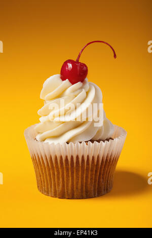 Cupcake mit roter Kirsche isoliert auf orange Stockfoto