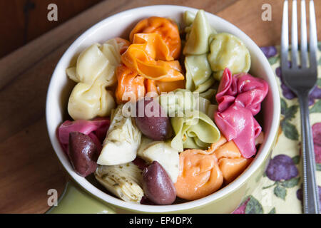 Farbenfrohe italienische Pastagericht serviert mit Artischockenherzen und Kalamata Oliven in einer Keramikschale für Mittag- oder Abendessen Stockfoto