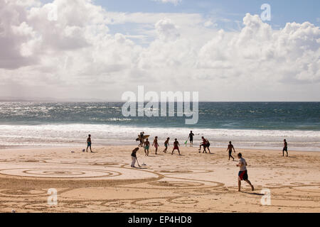 Menschen, die am Strand spielen, während ein Künstler Designs in den Sand in Byron Bay, Australien schafft. Stockfoto