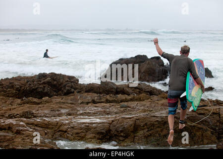 Eine Surfer verstärkt auf die Felsen in Byron Bay, Australien. Stockfoto
