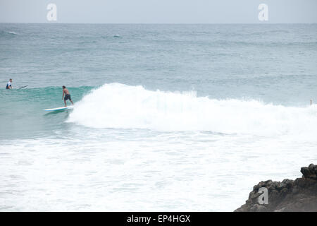 Eine Surfer fängt eine Welle auf seinem Longboard in Byron Bay, Australien. Stockfoto