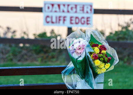 Ein Angebot von Blumen, befestigt auf einer Bank neben "Gefahr Cliff Edge" Schild über Dünenwanderungen Sand Strand von Perranporth, einem beliebten s Stockfoto